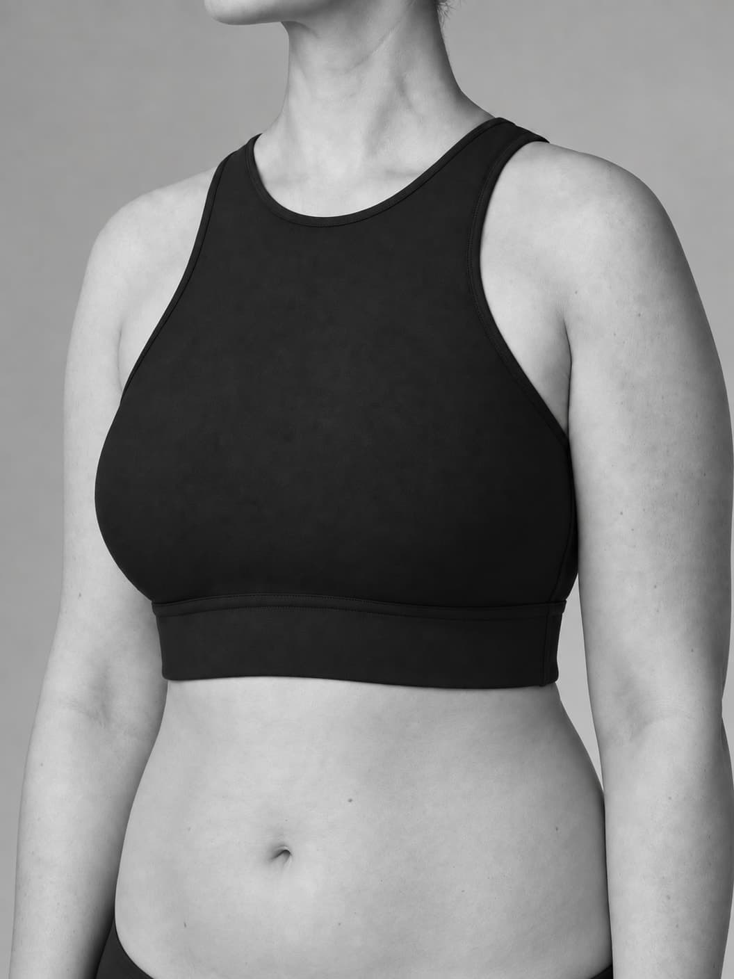 Black-and-white torso portrait with a high, rounded breast contour and a softly rounded abdomen