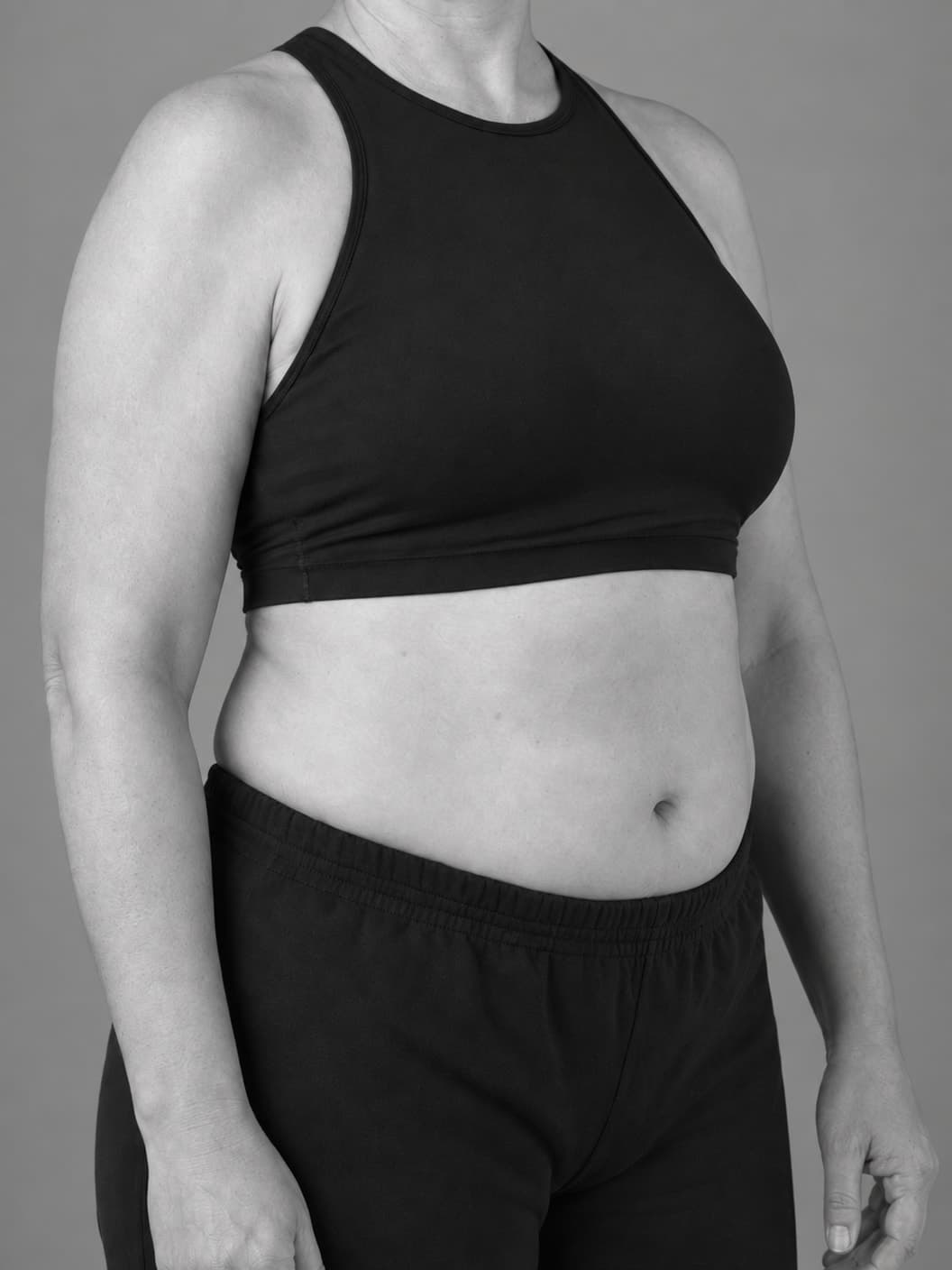 Monochrome close torso portrait showing a natural lifted contour on a woman with a softer build