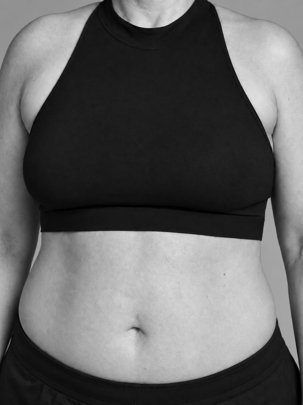 Monochrome close torso portrait showing a modest breast silhouette on a woman with a fuller build