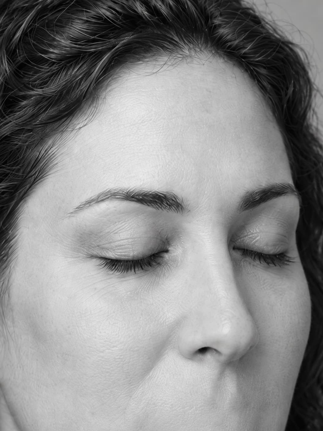 Black-and-white close-up of a woman's brows and closed eyelids