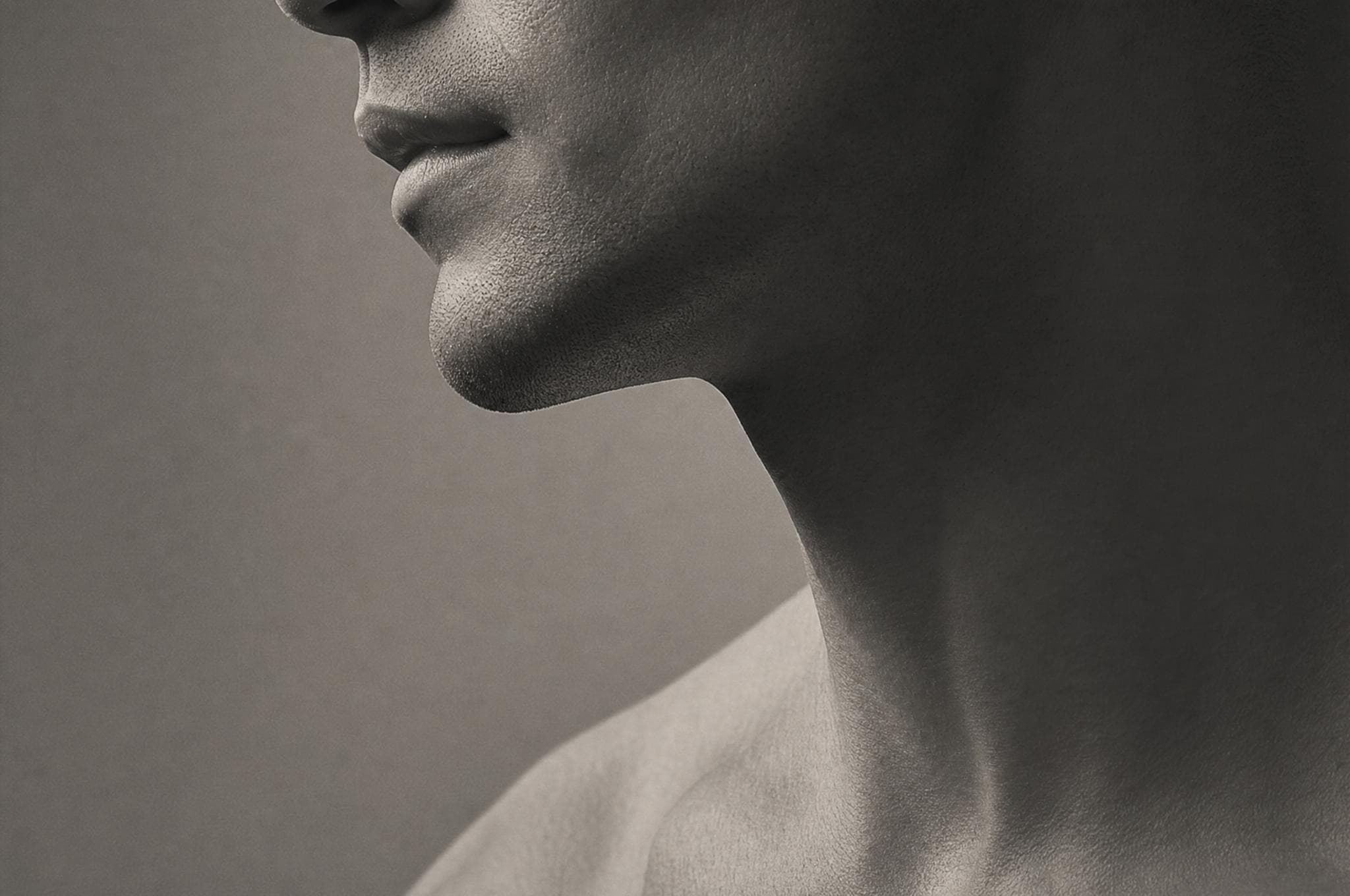 Sculptural study of a man's chin and jawline in soft shadow