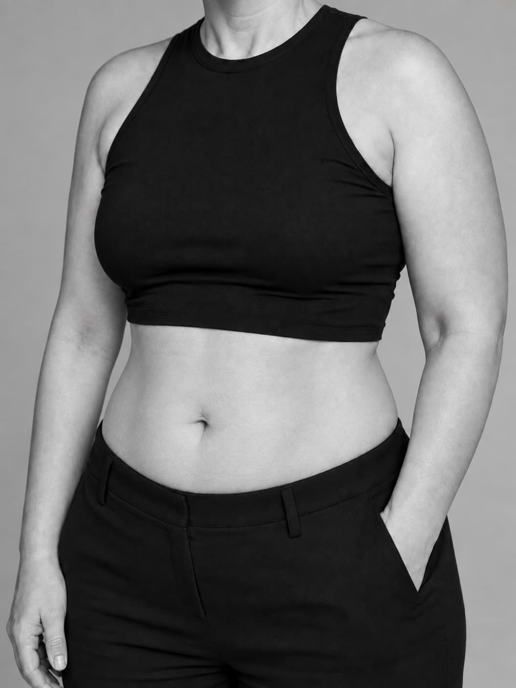 Black-and-white torso portrait showing a gently defined waist and natural abdominal softness