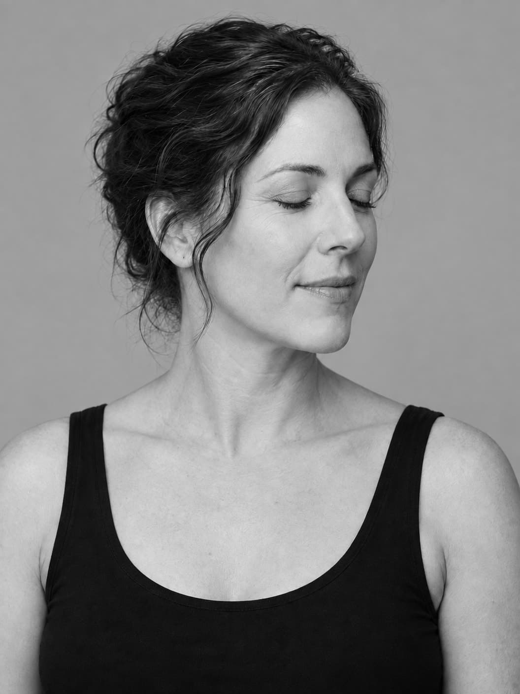 Monochrome three-quarter portrait of a woman with closed eyes and softly lit cheek and jaw contours