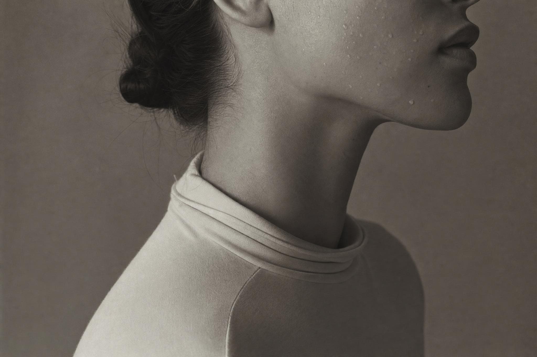 Close study of a woman's cheek and jaw with fine water droplets